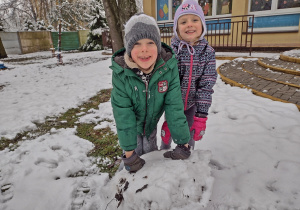 Dzieci toczą kulę śnieżną